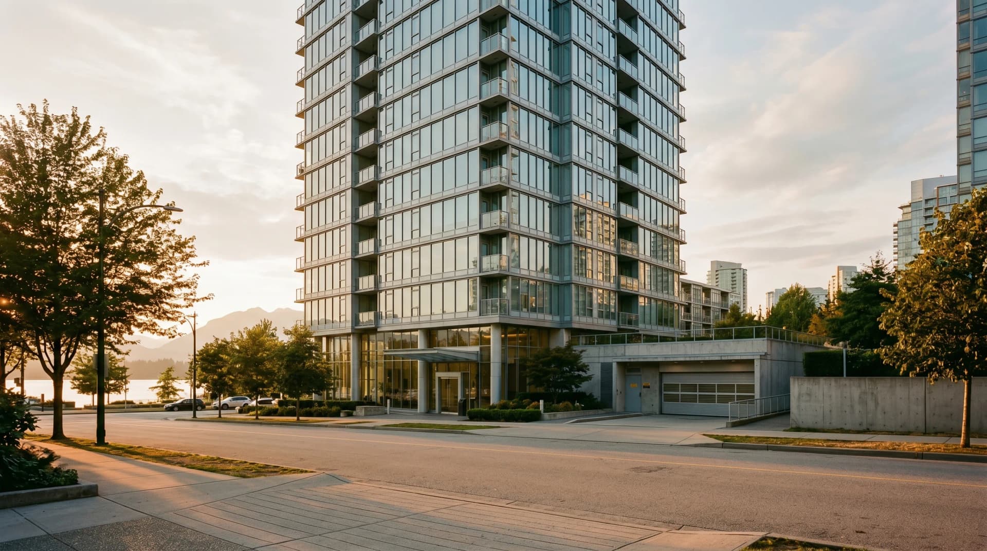 A Vancouver Coal Harbour glass-and-steel high-rise condo tower exterior with a service loading-dock entrance at the base — the building logistics we navigate for every condo install