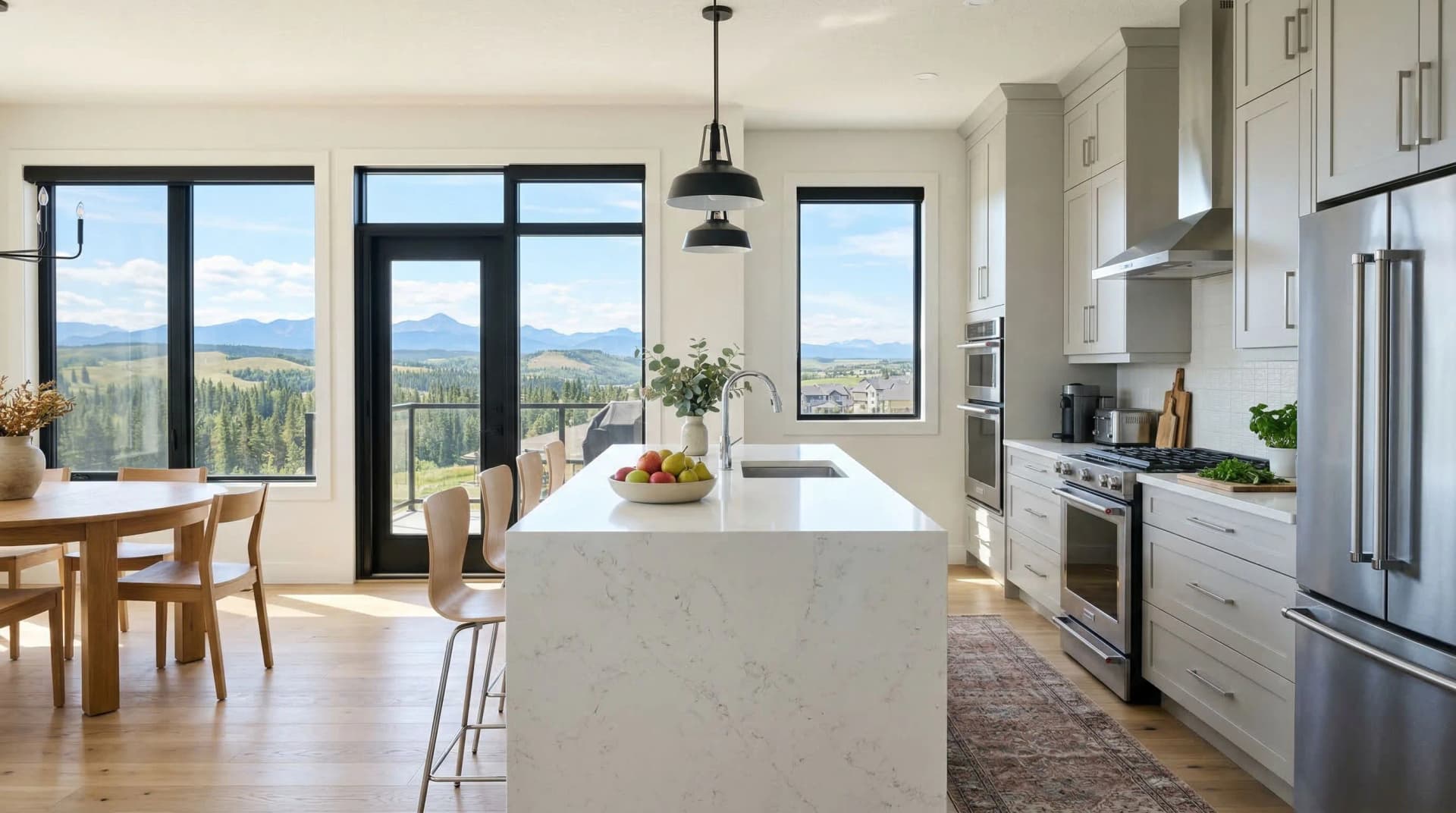 Distinctive Form — premium engineered quartz countertop with mitered waterfall island edge in a bright contemporary Airdrie, Alberta kitchen. White marble-veined quartz surface with eased edge, white shaker cabinetry, black industrial pendant light, stainless steel appliances, and panoramic views of Alberta foothills and distant Rocky Mountains through floor-to-ceiling windows. Professional countertop fabrication and installation serving Airdrie and surrounding areas.