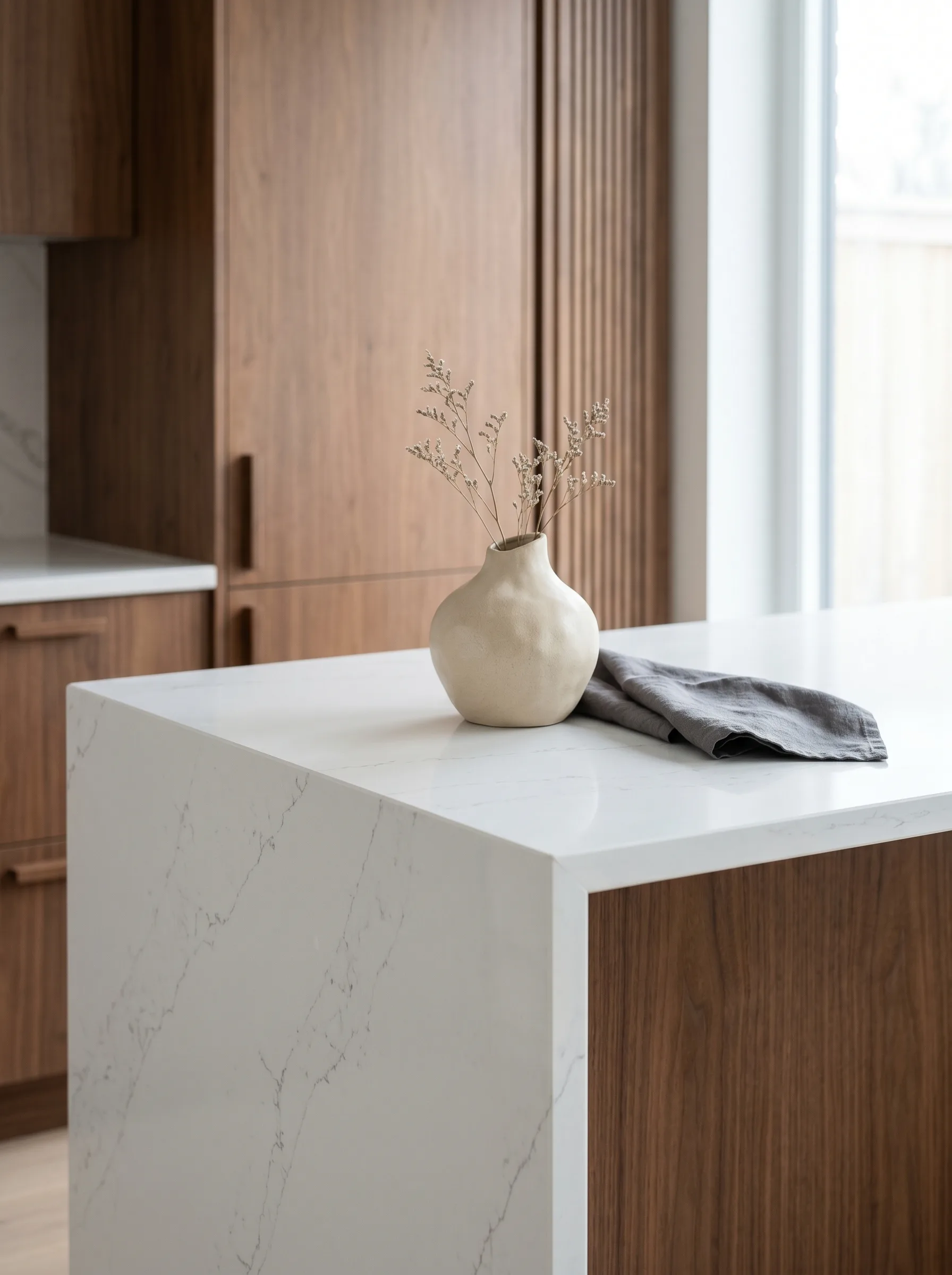 Tight interior-design vignette of a polished white engineered porcelain slab with subtle cool grey veining set against warm walnut millwork — Distinctive Form premium porcelain