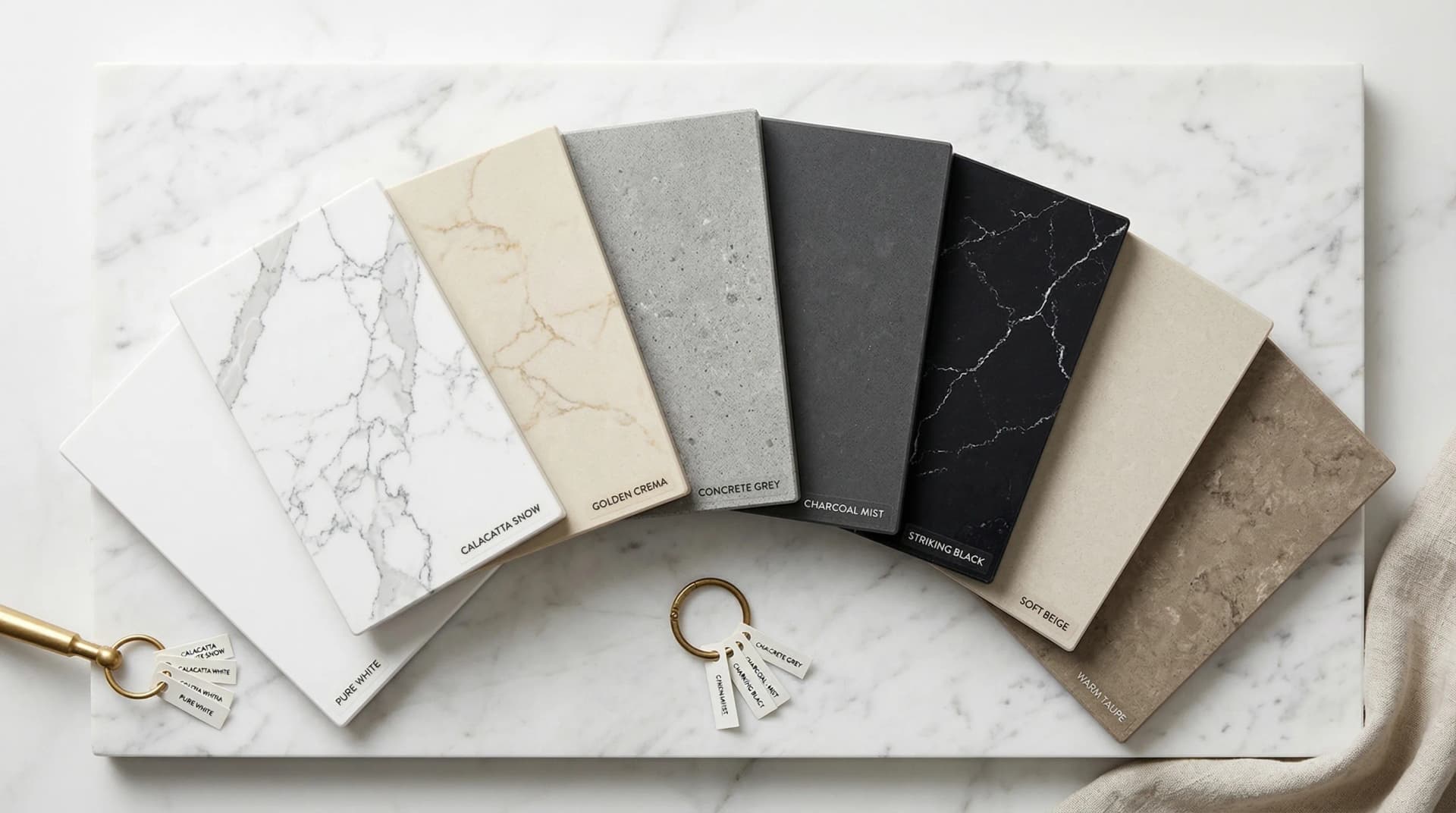 Distinctive Form — engineered quartz colour and pattern variety. An elegant overhead arrangement of multiple polished engineered quartz countertop samples fanned out showing the full range of available colours and patterns: pure white, Calacatta white with grey veins, warm cream with gold veining, cool grey concrete look, deep charcoal, dramatic black with white veining, soft beige, and warm taupe — demonstrating how modern manufacturing technology produces thousands of colour options from solid neutrals to dramatic veined designs.