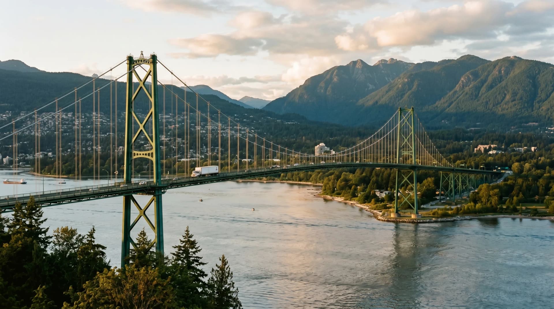 The iconic green-painted steel Lions Gate Bridge spanning Burrard Inlet between Vancouver and North Vancouver at golden hour with the dark green Coast Mountain ridgeline of the North Shore beyond and a single delivery truck for scale — Distinctive Form serves North Vancouver